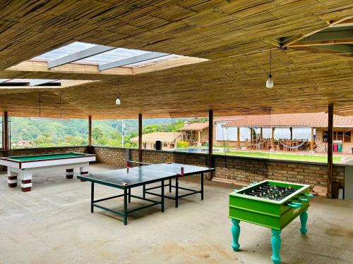 two ping pong tables in a large room with windows at Vistabamba Ecuadorian Mountain Hostel in Vilcabamba