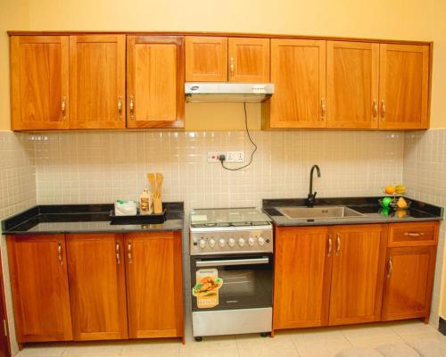 cocina con armarios de madera, fogones y fregadero en Nellly's Rest House, en Dar es Salaam