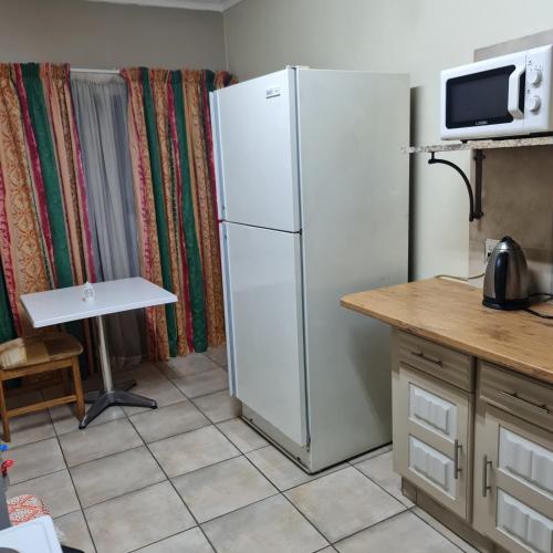 a kitchen with a white refrigerator and a table at Capital Hill Stay at Spa in Pretoria