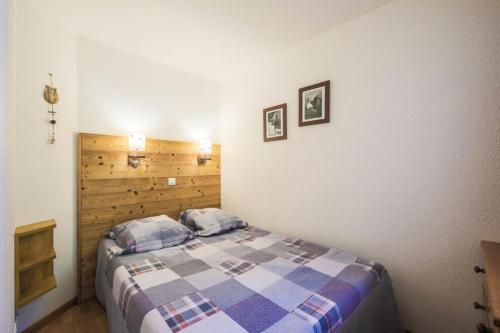 une chambre avec un lit et une tête de lit en bois dans l'établissement Résidence Les Constellations - maeva Home - Appartement 2 Pièces 5 Personnes - Confort MAE-3350, à La Plagne Tarentaise