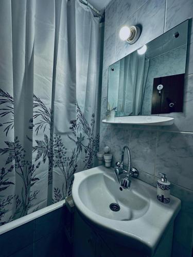 a bathroom with a sink and a shower curtain at Apartament ASK HOME in Slănic-Moldova