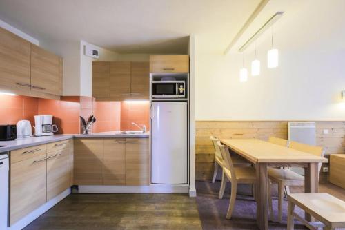 une cuisine avec une table et un réfrigérateur dans l'établissement Résidence Les Gémeaux - maeva Home - Appartement 2 pièces 5 personnes - Confort MAE-3621, à La Plagne Tarentaise