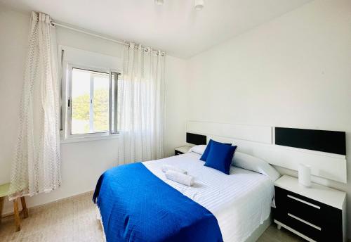 Schlafzimmer mit einem blauen und weißen Bett und einem Fenster in der Unterkunft BOOK SOLEMIO MIAMI PLAYA - ONLY FAMILIES in Miami Platja