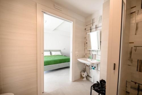 ein Schlafzimmer mit einem grünen Bett und einem Waschbecken in der Unterkunft BLU MARINE in Catanzaro