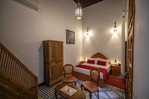 a bedroom with a bed and a table and chairs at Riad Jamal in Fès