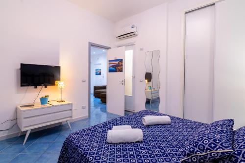 um quarto com uma cama azul e uma televisão em ARIA DI MARE ROOMS em Cefalù