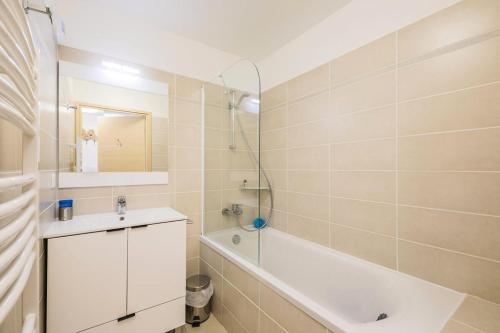 uma casa de banho com uma banheira branca, um lavatório e uma banheira tubermott em Résidence Les Mélèzes - maeva Home - Appartement 2 Pièces 4 Personnes - S 35 em Le Dévoluy
