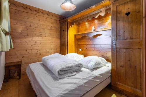 un lit dans une chambre avec un mur en bois dans l'établissement Résidence Les Fermes de Méribel - maeva Home - Appartement 2 Pièces 4 Personnes - Sélection MAE-4817, à Les Allues