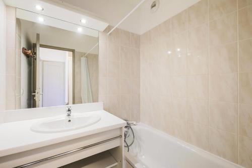 a bathroom with a sink and a tub and a mirror at Résidence Le Hameau des Ecrins - maeva Home - Appartement 2 Pièces 6 Person 50 in Puy-Saint-Vincent