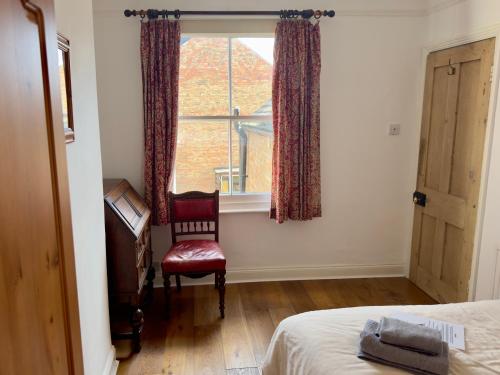 een slaapkamer met een stoel en een raam bij One Home in Oxford