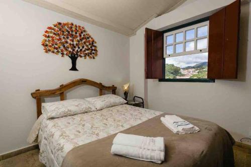 a bedroom with a bed with a tree on the wall at Casadinha - Casa no centro histórico de Ouro Preto in Ouro Preto