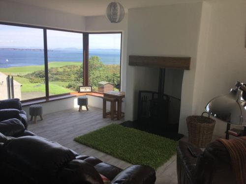 a living room with a couch and a large window at Kinbane Self Catering Cottages - 'Makem's Cottage' in Ballycastle
