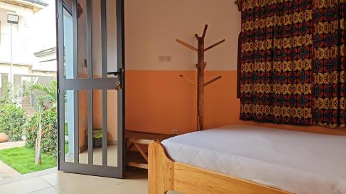 a bedroom with a bed next to a glass door at Hotel Eyram Kpalime in Palimé