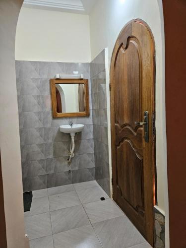 a bathroom with a wooden door and a sink at Hotel Eyram Kpalime in Palimé