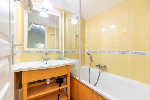 une salle de bain avec un lavabo, une baignoire et un miroir dans l'établissement Les Maisons de Port Bourgenay - maeva Home - Maison cosy 3 pièces 6 personnes - Sélection - super Home MAE-6401, à Talmont-Saint-Hilaire