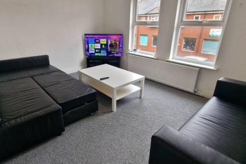 een woonkamer met een bank, een tafel en een tv bij Comfy Apartment - Nottingham Centre - Free Parking in Nottingham