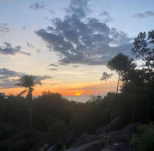 a sunset with a palm tree and the sky at Blue Elephant Villa Koh Phangan in Haad Pleayleam