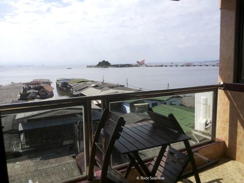 a balcony with a chair and a view of the water at Seaview Sriracha Hotel in Si Racha
