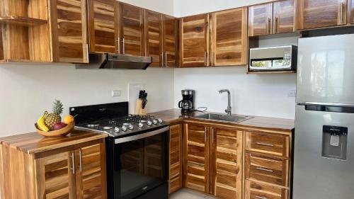 a kitchen with wooden cabinets and a stove top oven at Canavida Villas & Resort in Uvita