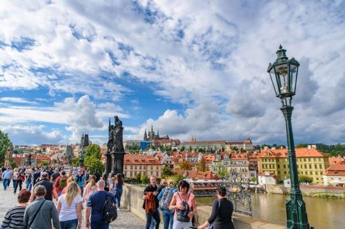 a crowd of people walking on a bridge over a river at Wishlist Prague Residences - Charles Bridge Karlova in Prague