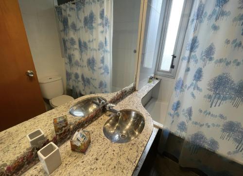 a bathroom with a sink with a shower curtain at Pichincha Guemes Balcon in Rosario