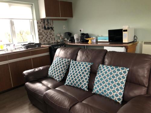 un sofá de cuero marrón con dos almohadas en la cocina en Riverside en Doonbeg