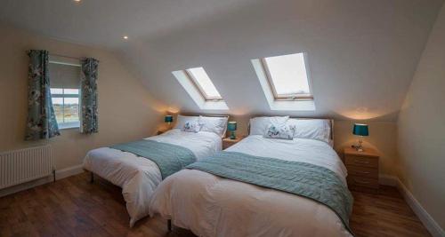 two beds in a room with two windows at Islandcorr Farm Luxury Glamping Lodges and Self Catering Cottage, Giant's Causeway in Bushmills