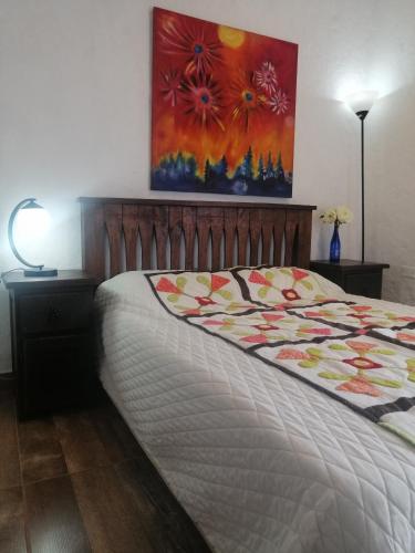 a bedroom with a bed and a painting on the wall at Apartaestudios La Baranda in Salento