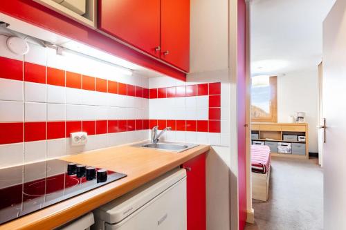 une cuisine avec des carreaux rouges et blancs sur le mur dans l'établissement Résidence Plagne Lauze - maeva Home - Studio 4 Personnes - Confort MAE-5774, à Mâcot La Plagne