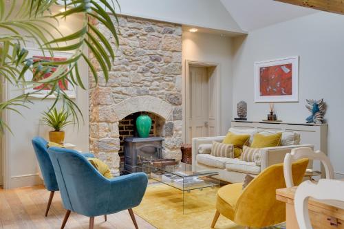 a living room with a couch and a stone fireplace at Pope Lodge: Stunning Stone Coach House Conversion in Alnmouth