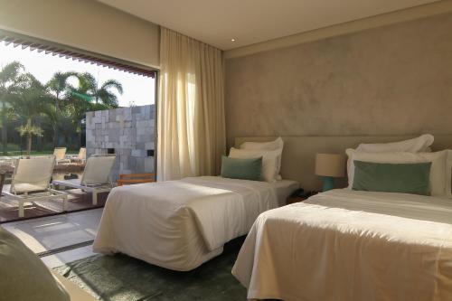a bedroom with two beds and a large window at île de Pipa - Ma Plage Hotel in Pipa