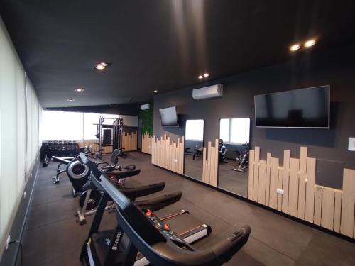 a gym with a row of tread machines and a flat screen tv at Garden Plaza in San Miguel de Tucumán