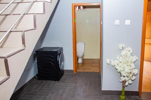 a bathroom with a toilet and a television in a hallway at Accra cosy homes near beaches and mall in Accra