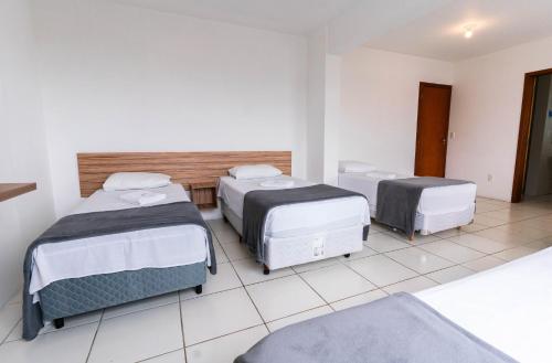 a room with three beds in a room at Praia Comprida Hotel in São José
