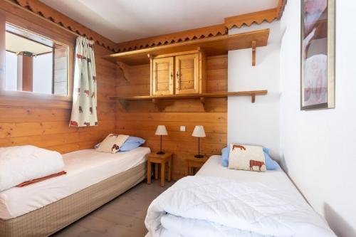 deux lits dans une chambre aux murs en bois dans l'établissement Résidence Les Hauts Bois - maeva Home - Appartement 3 Pièces 8 Personnes - Sélection MAE-8034, à Aime La Plagne