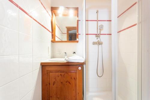 y baño con lavabo y ducha con espejo. en Résidence Les Hauts Bois - maeva Home - Appartement 3 Pièces 8 Personnes - 034, en Aime La Plagne
