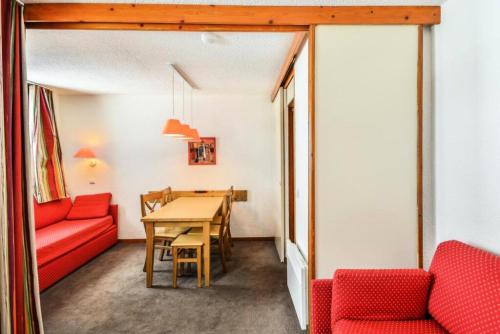 une salle à manger avec une table et des chaises rouges dans l'établissement Résidence Les Chalets des Arolles - maeva Home - Studio 4 Personnes - Confort MAE-8704, à La Plagne Tarentaise