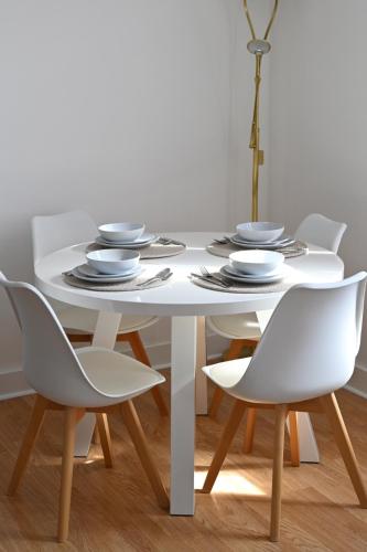 a white dining table and chairs with plates and dishes at Unique and luxury city center apartment with free parking in Southampton