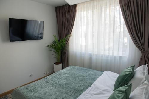 a bedroom with a bed and a tv and a window at Cosy retreat in Piatra Neamţ