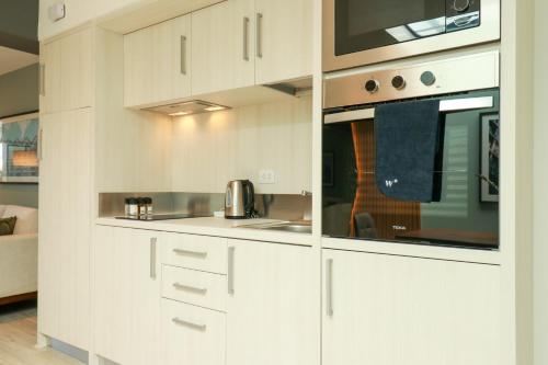 a kitchen with white cabinets and a microwave at Primera Parada By Wynwood House in Lima