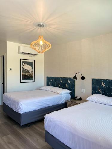 a hotel room with two beds and a chandelier at Anaheim Maingate Inn in Anaheim