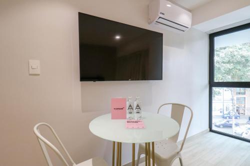 a white table with chairs and a tv on a wall at Primera Parada By Wynwood House in Lima