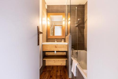 une salle de bain avec un lavabo, une baignoire et un miroir dans l'établissement Résidence Les Néreïdes - maeva Home - Appartement 3 pièces 7 personnes - Prestige MAE-2704, à La Plagne Tarentaise