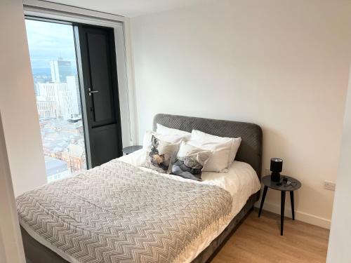 2bedroom luxury apartment city centre V في مانشستر: غرفة نوم بسرير مع نافذة كبيرة
