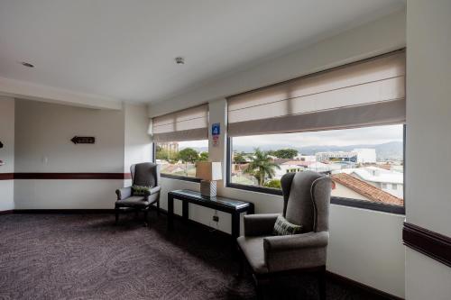 a room with two chairs and a desk and two windows at Parque del Lago Boutique Hotel in San José