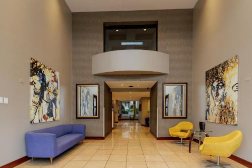 a lobby with a blue couch and yellow chairs at Parque del Lago Boutique Hotel in San José