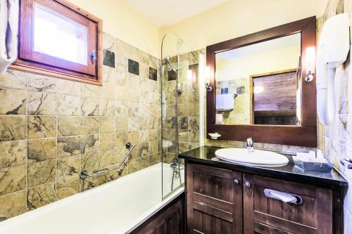 une salle de bain avec un lavabo, une baignoire et un miroir dans l'établissement Résidence Les Arcs 1950 Le Village - maeva Home - Appartement 3 pièces 4 personnes - Sélection MAE-3984, à Bourg-Saint-Maurice