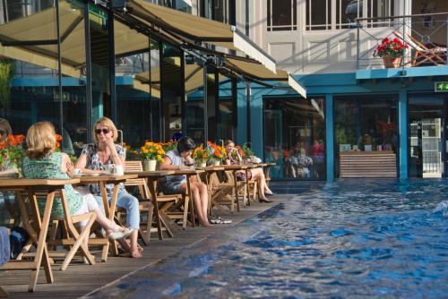 a group of people sitting at tables by a swimming pool at Lido Townhouse in Bristol