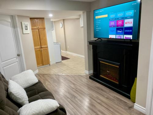 a living room with a tv and a couch and a fireplace at 1 room in a cozy and beautiful basement in Guelph