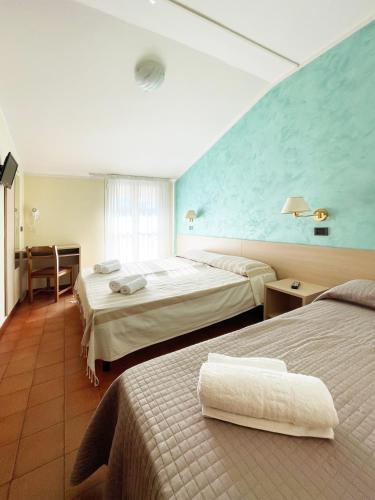 una camera d'albergo con due letti e una parete blu di Hotel Reale a Rimini